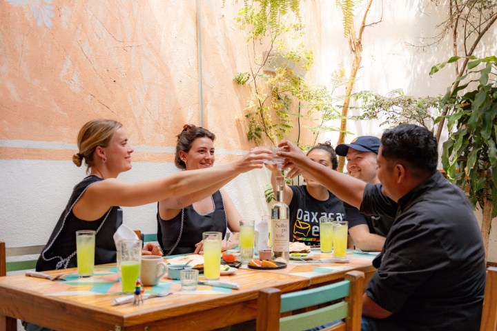 Group of friends toasting with drinks at an outdoor cafe table.