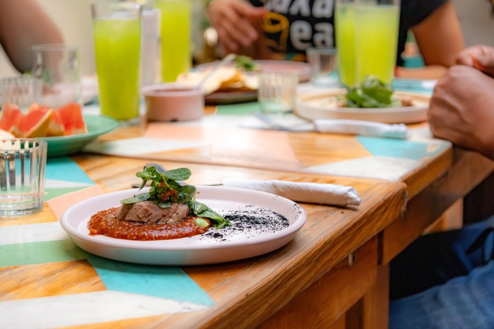 Plate with gourmet dish on table set with drinks and other plates.